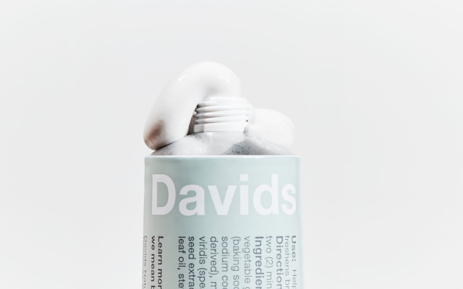 Davids dantų pastos išspausta tubelė šviesiame fone.