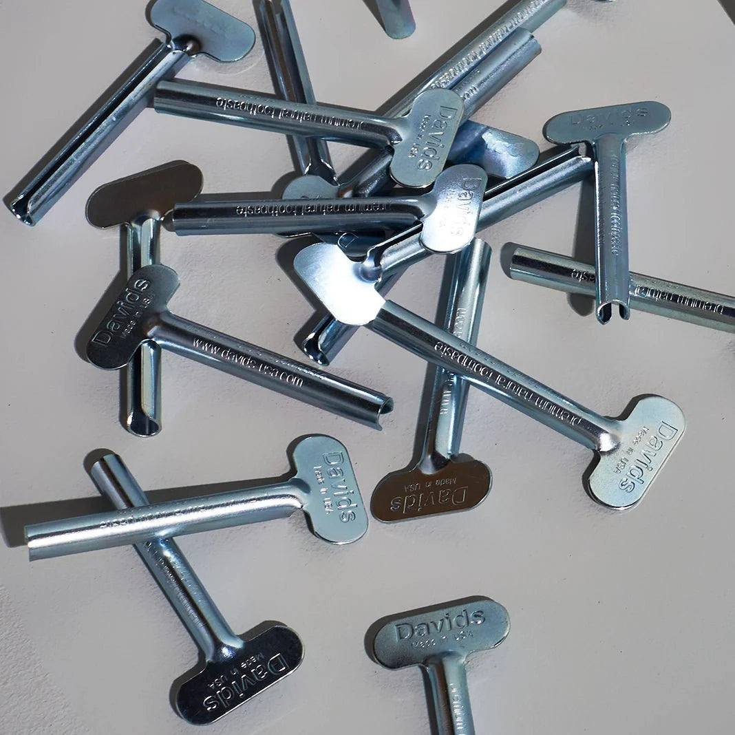 Davids spaustukai metalinėms dantų pastos tūbelėms, pilkame fone.