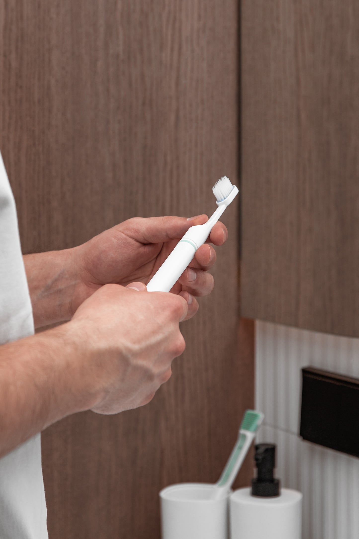 Tromatz bioelektrinis dantų šepetėlis vyro rankose, atvaizduotas vonios kambaryje.