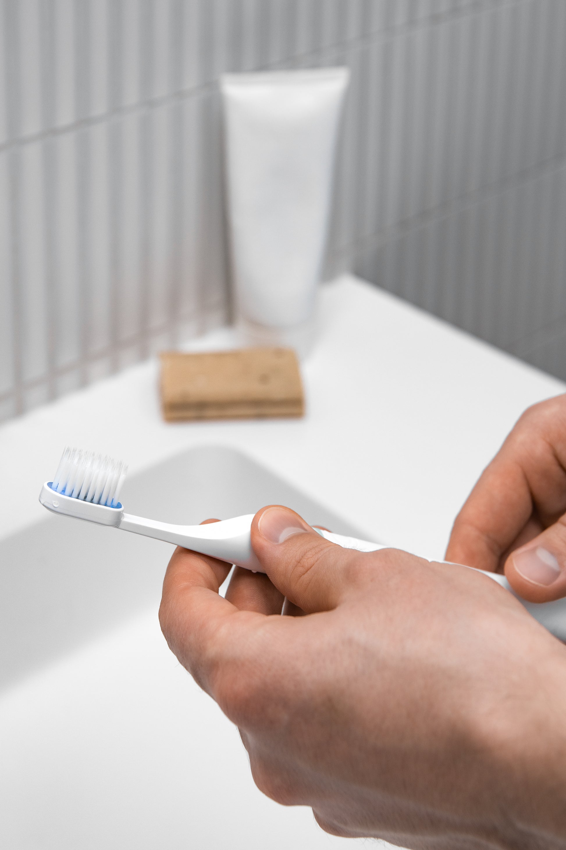 Tromatz bioelektrinis dantų šepetėlis vyro rankose, atvaizduotas šviesiame vonios kambaryje.