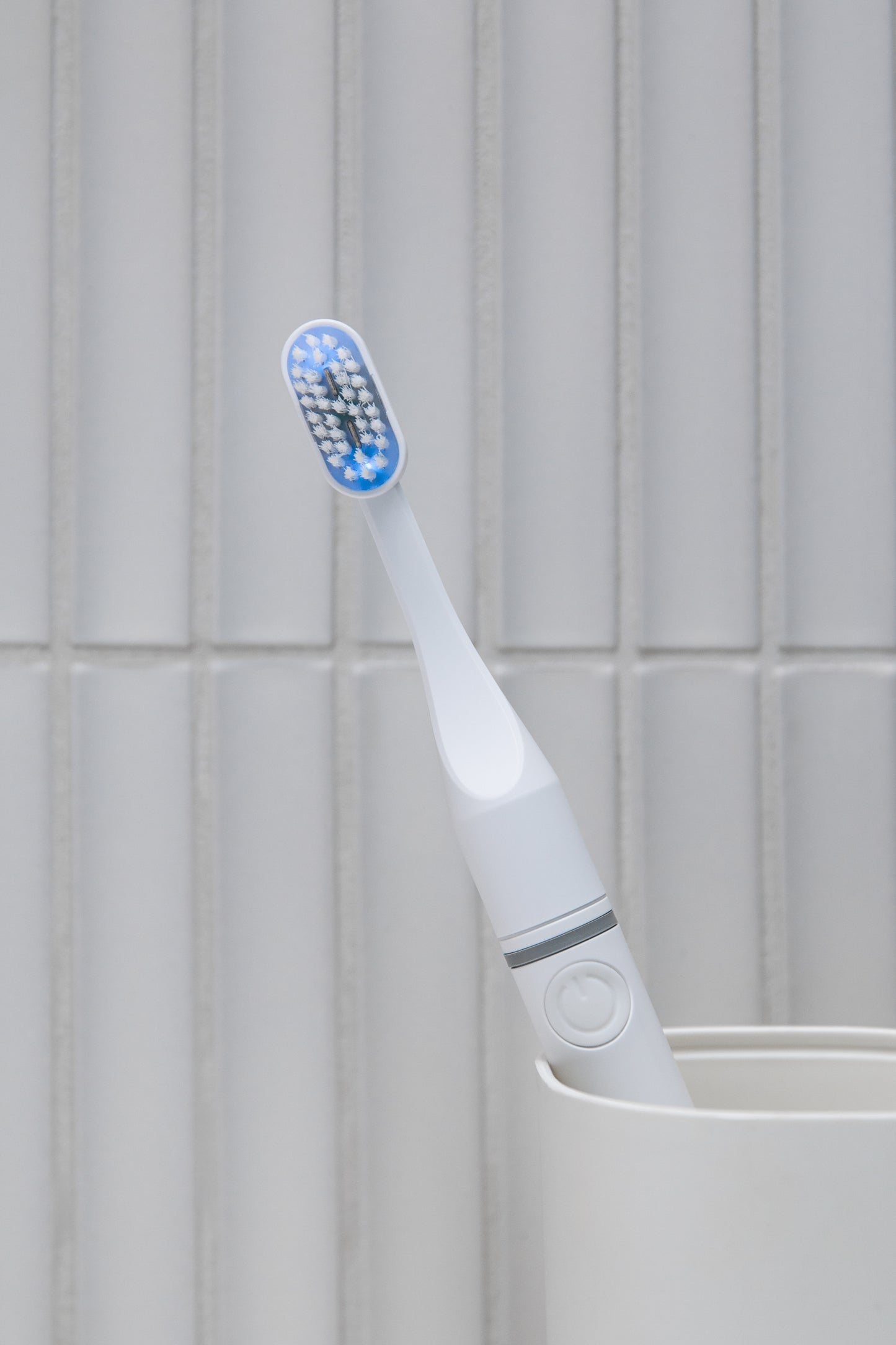 Tromatz Pro bioelektrinis dantų šepetėlis šviesiame vonios kambaryje, padėtas šepetėlių indelyje.