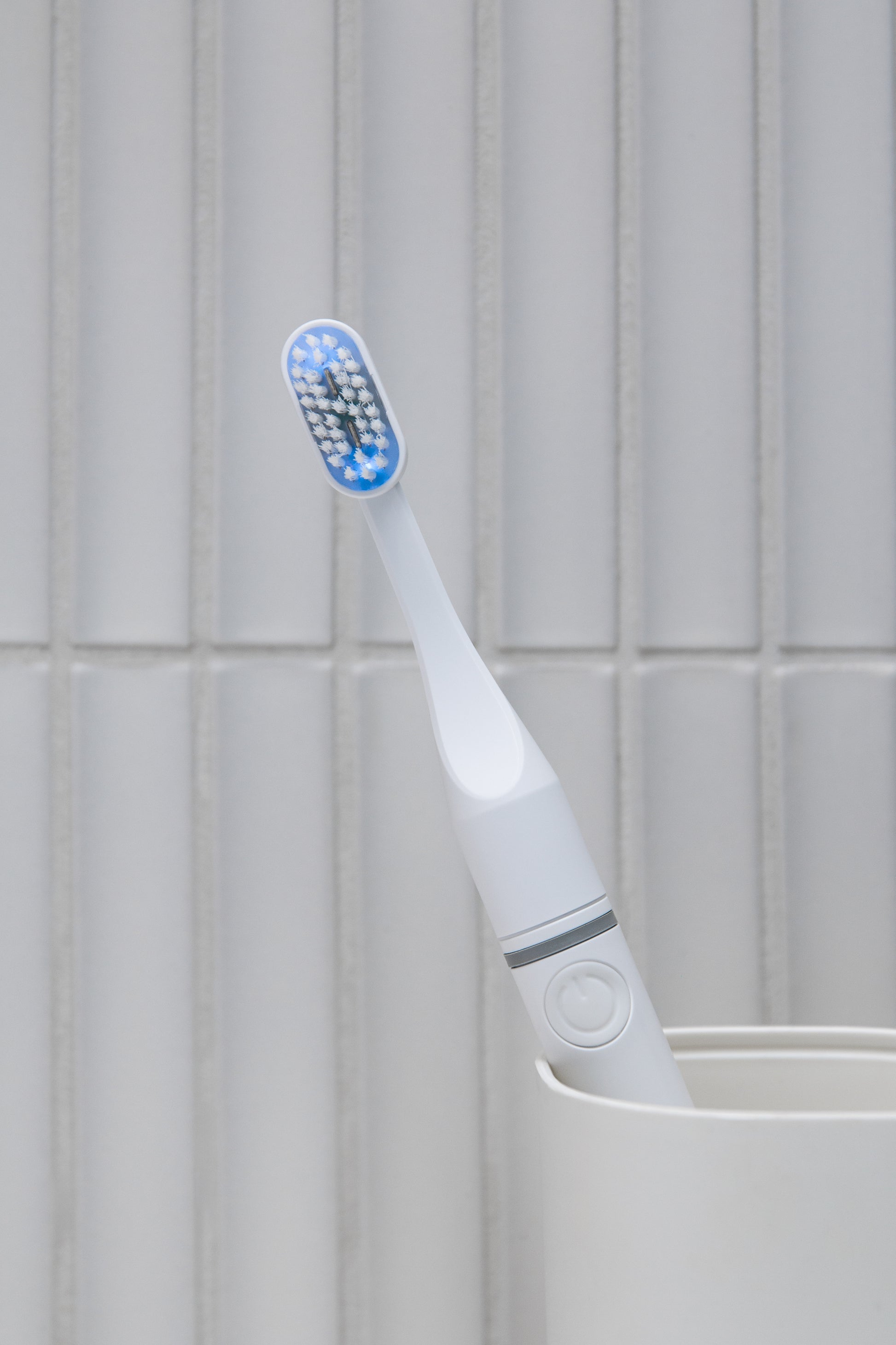 Tromatz Pro bioelektrinis dantų šepetėlis šviesiame vonios kambaryje, padėtas šepetėlių indelyje.