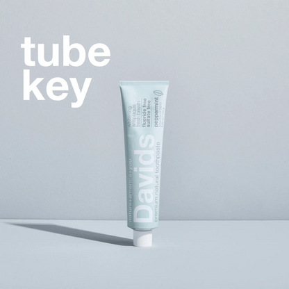 Davids spaustukas metalinėms dantų pastos tūbelėms naudojimo metu, spaudžiant pipirmėtės skonio dantų pastą.